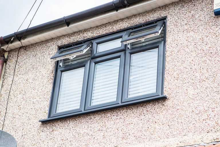 Modern triple casement window with white blinds installed in tan brick wall of residential building