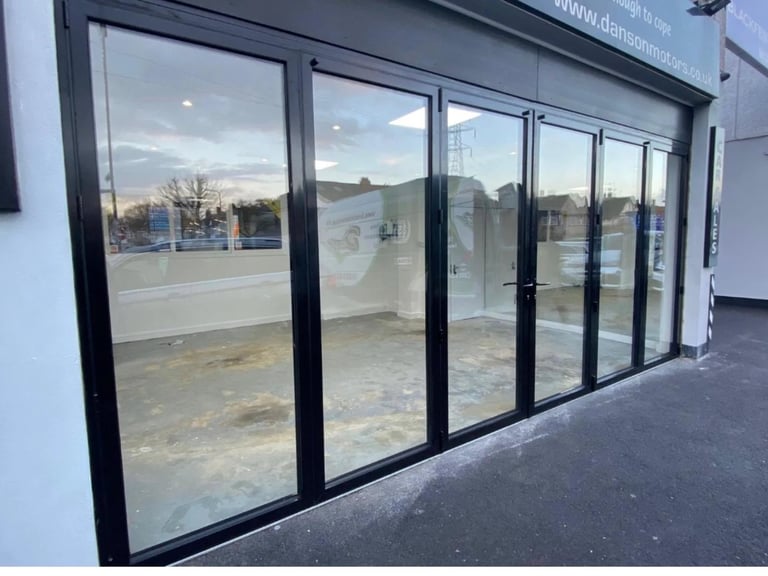 Modern storefront with large black-framed glass doors and windows displaying empty retail interior space