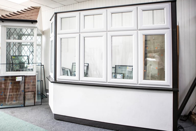 White-framed window and door display unit with multiple glass panels in a showroom setting